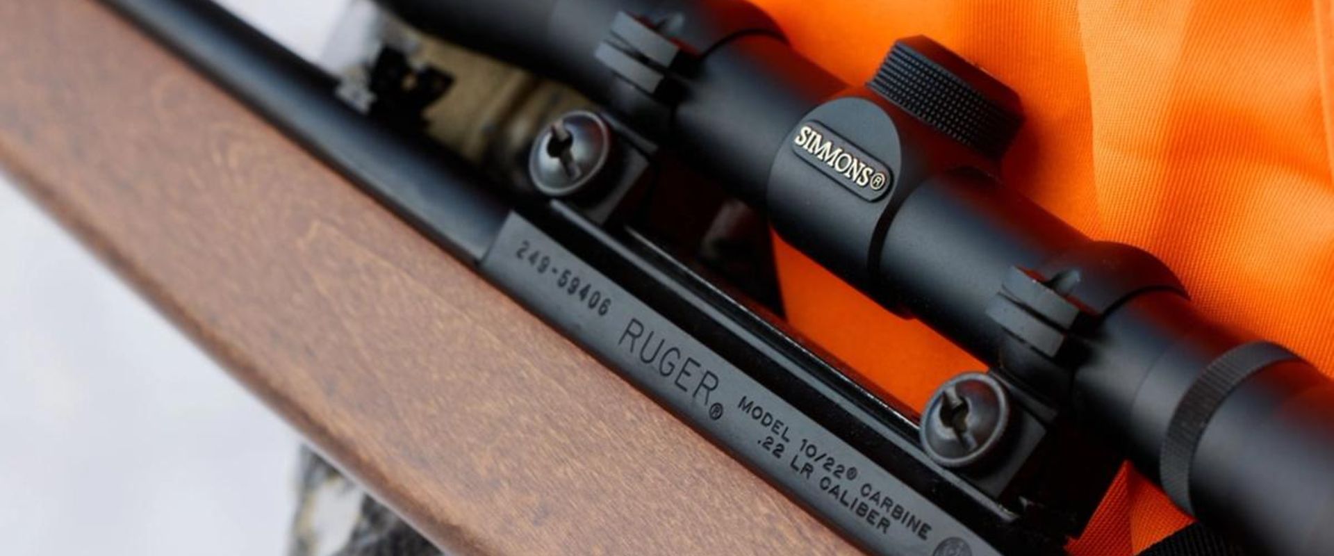 Close-up of hunter's orange vest and small game rifle, rabbit hunting gear list concept.