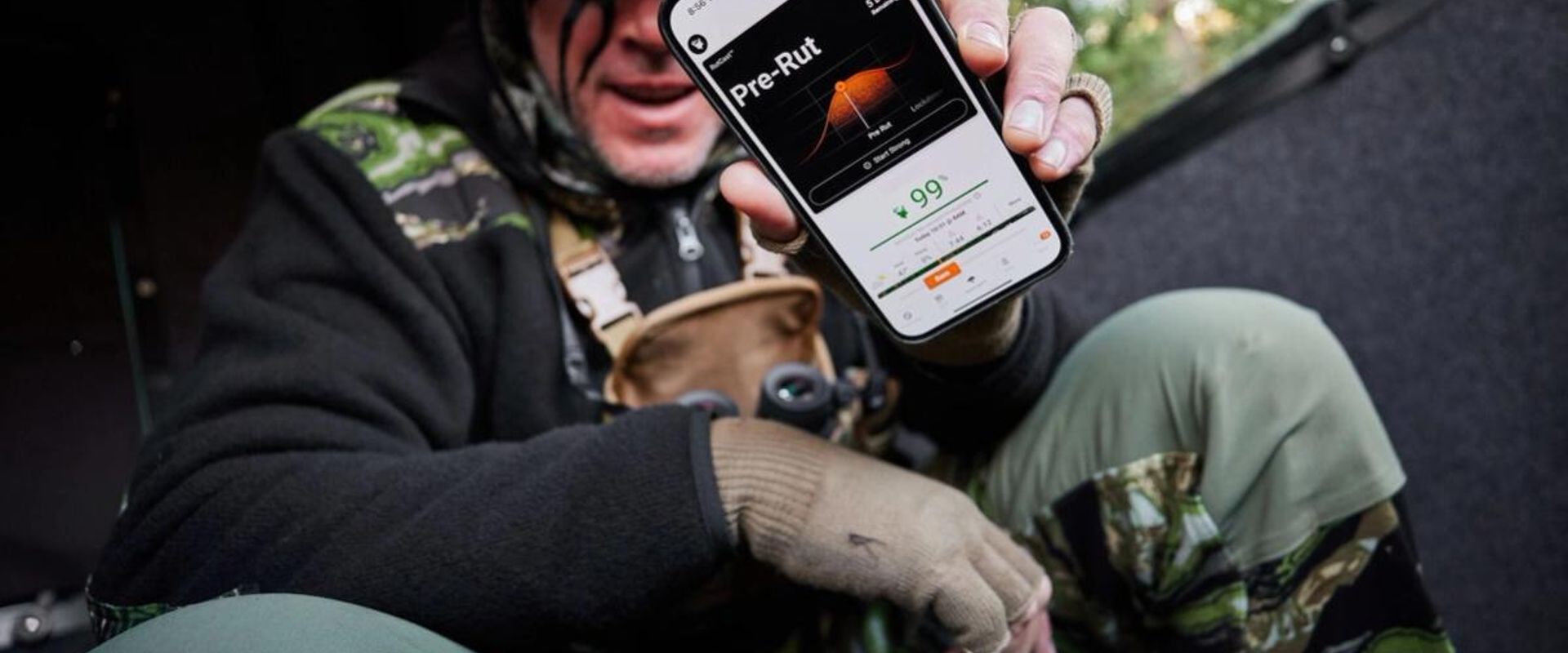 John Dudley holds up a phone showing the HuntWise hunting app RutCast feature.