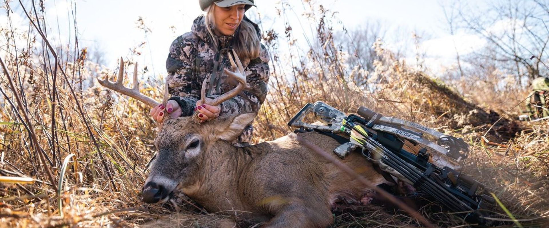 A female hunter shows off a deer after a hunt, women's hunting gifts concept.