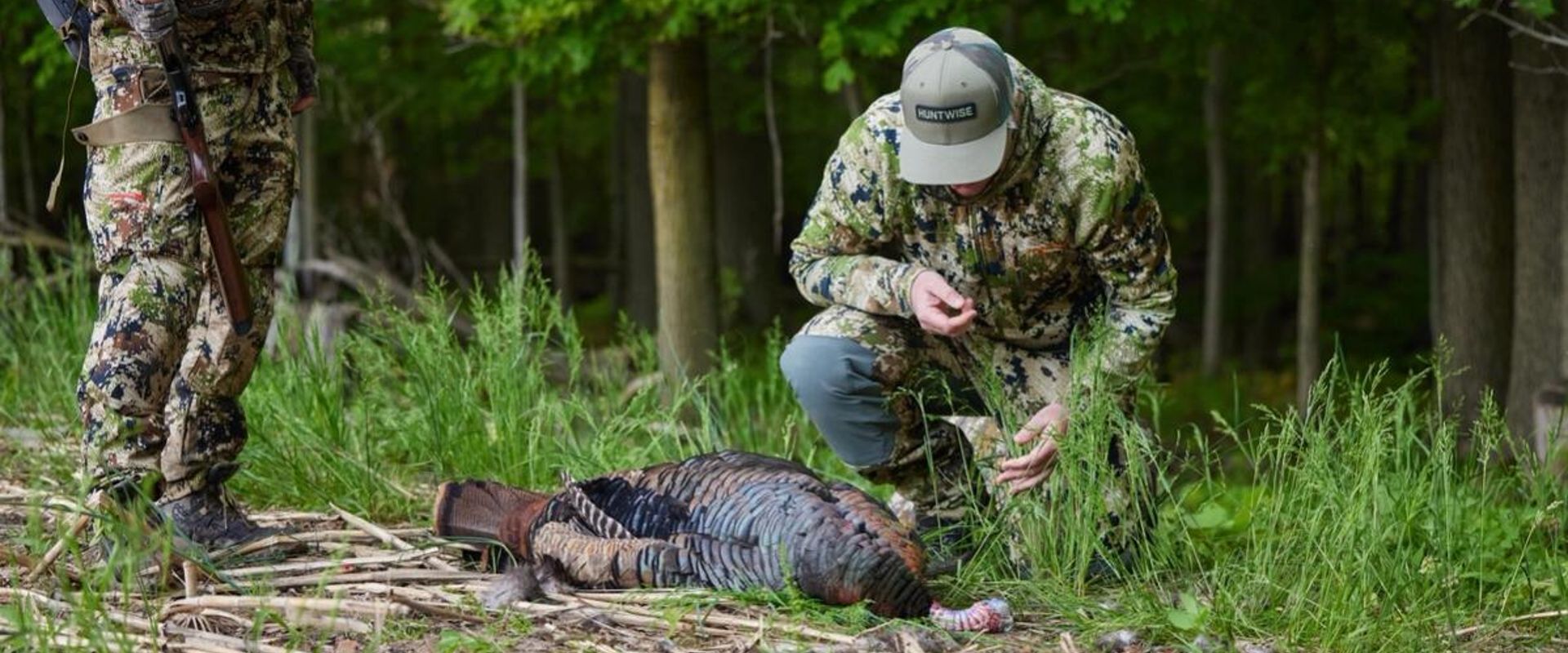 A hunter kneels next to a turkey kill, where to shoot a turkey concept.