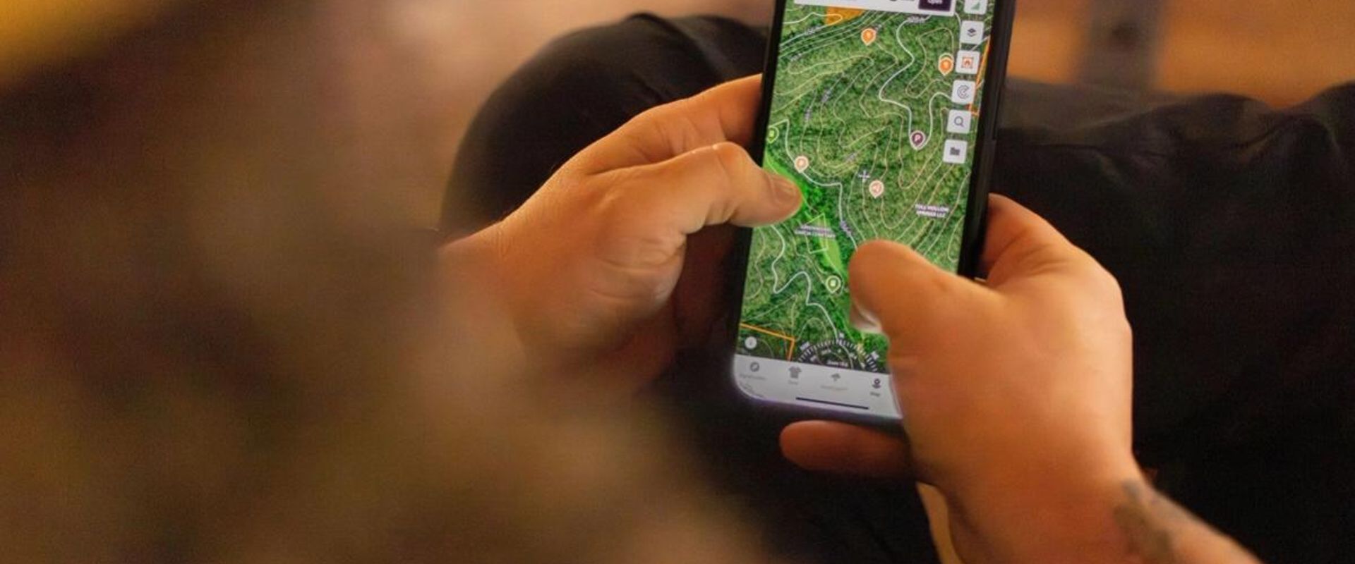 Close-up of hunter using phone showing topo map, how to read topo maps for deer hunting concept.