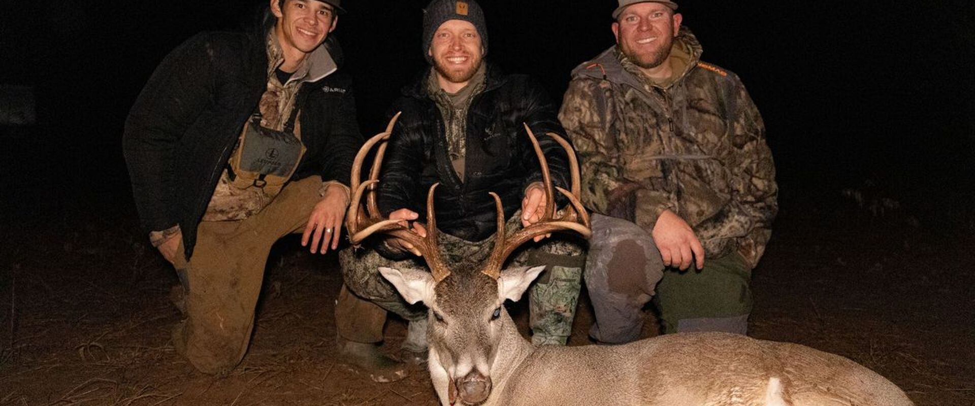 Three hunters smile with a deer after a successful hunt, meat for holiday venison recipes concept.
