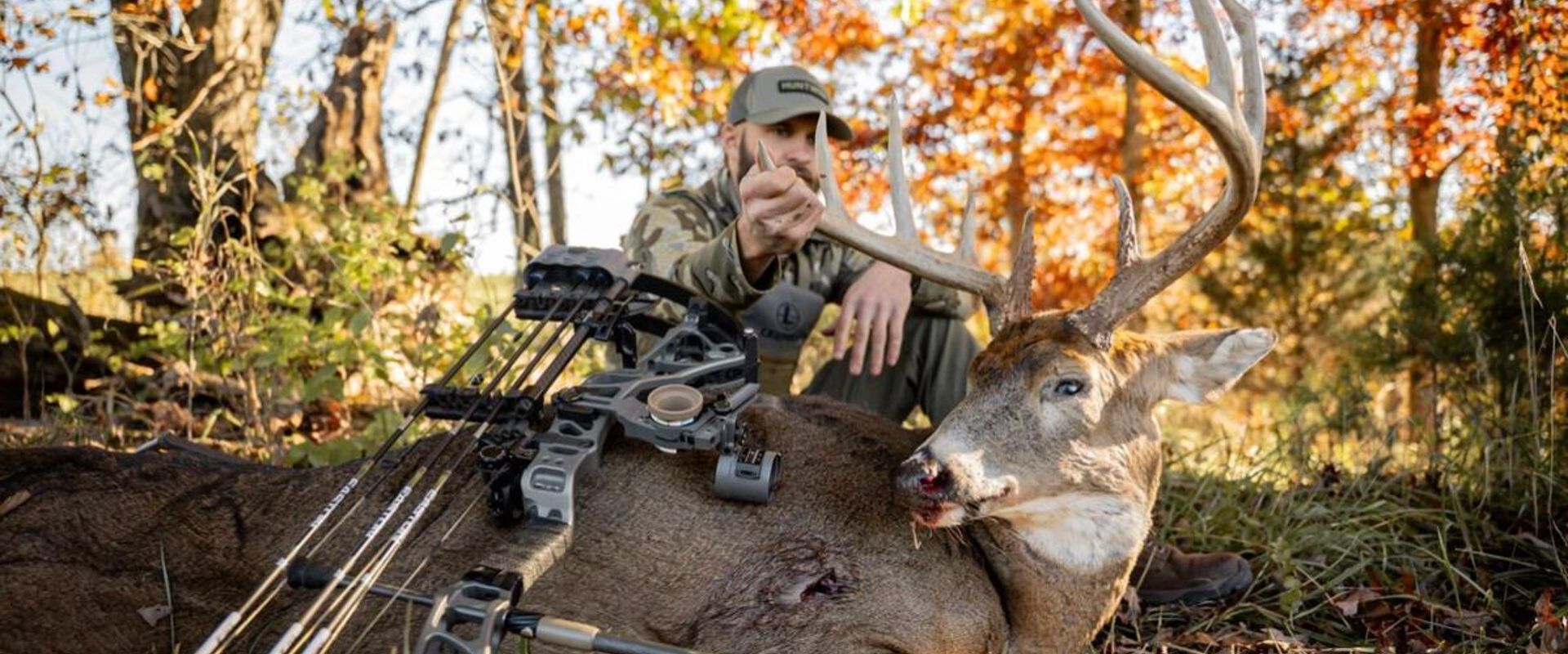 Hunter with buck deer and bow after hunt, represents post season bow maintenance.