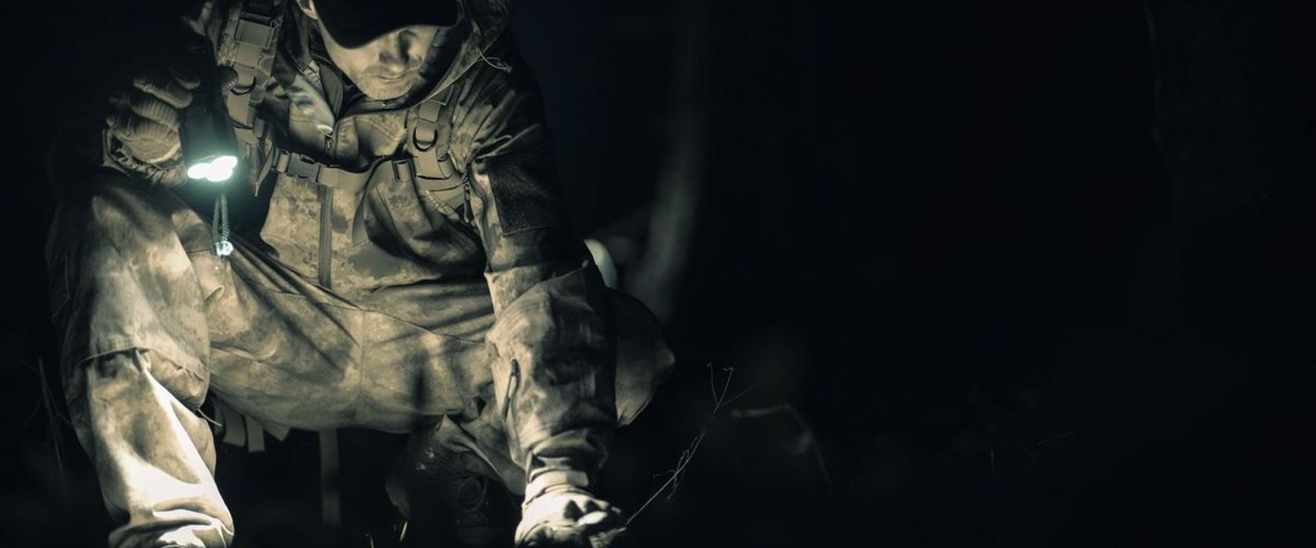 A hunter in camo with a flashlight in the dark, coyote hunting at night concept.