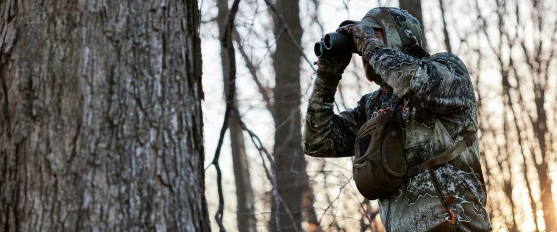 Hunter using binoculars in the woods to scout, turkey scouting concept.