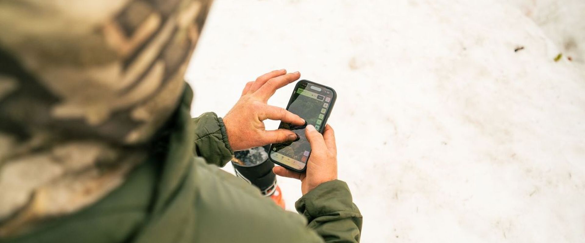 Hunter using phone with HuntWise on screen, how to find mule deer concept.