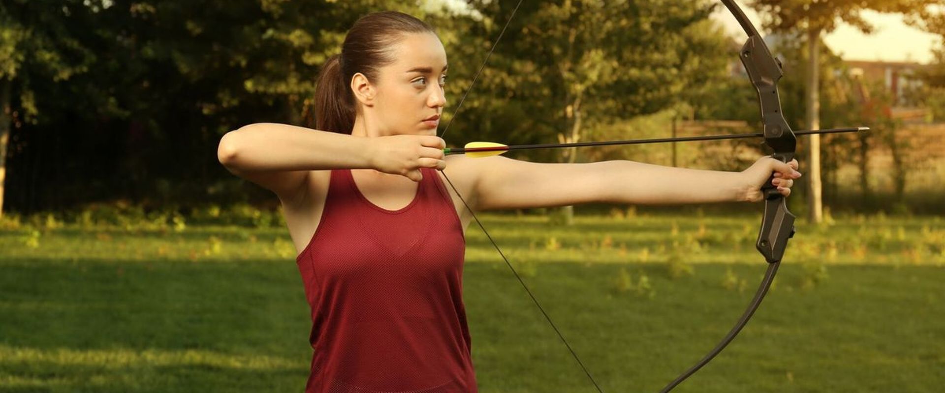 A woman draws a recurve bow.