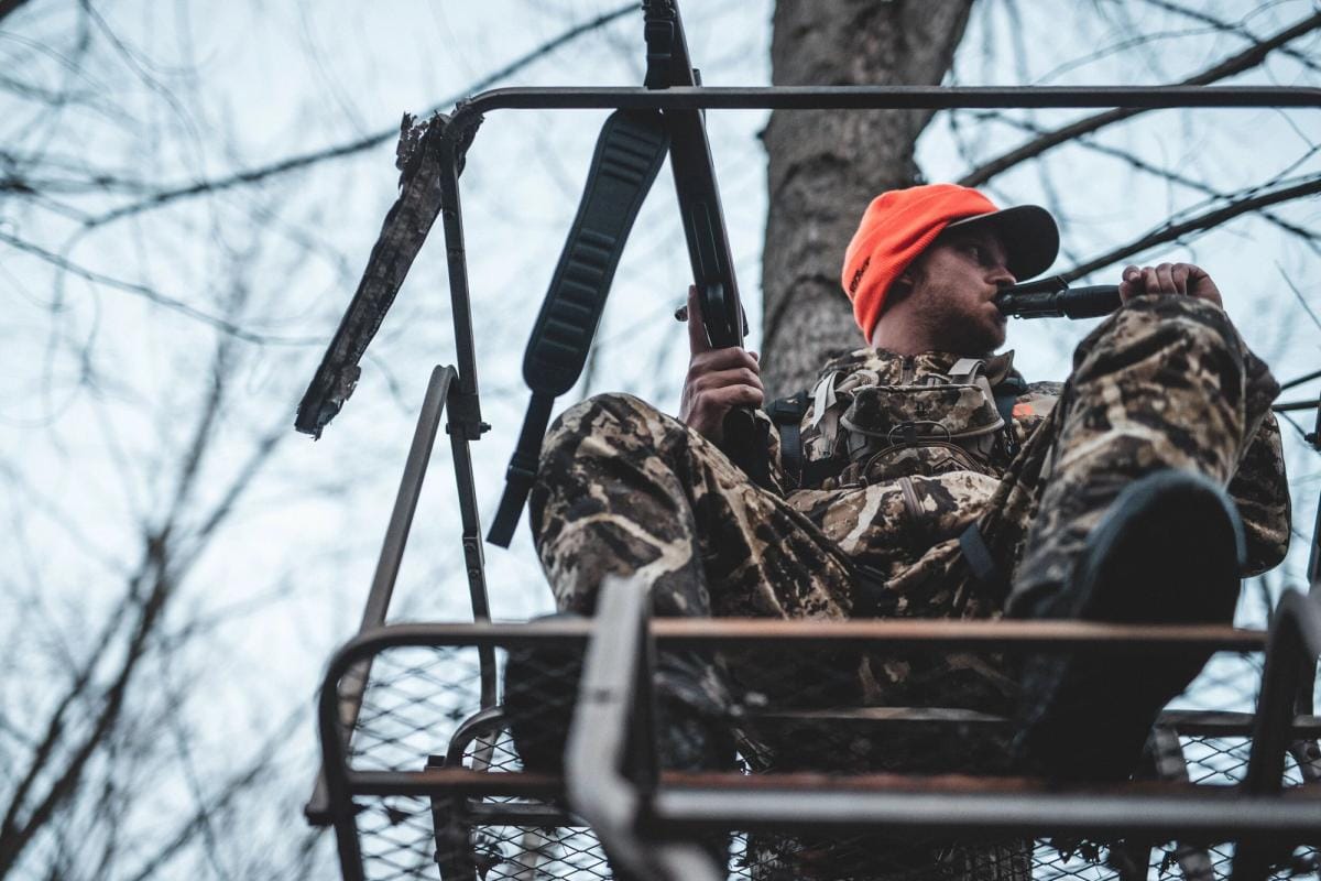 A hunter uses a deer call, calling bucks concept.