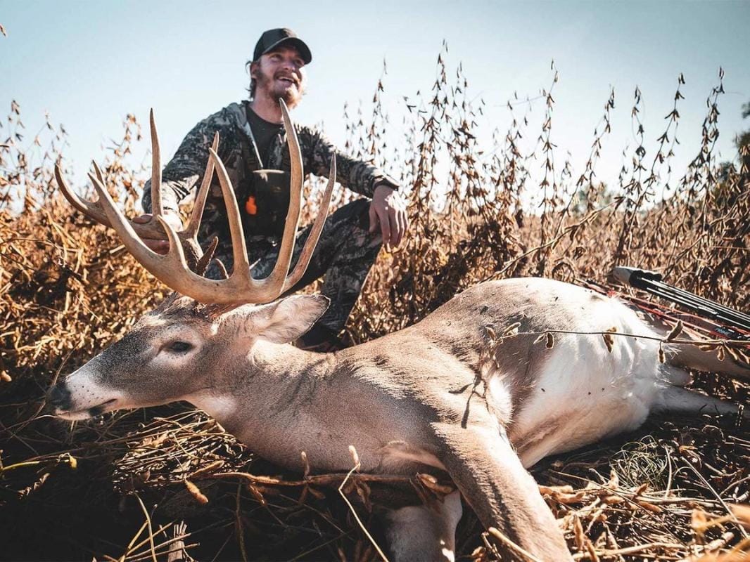A hunter with a deer after a kill shot, hunting whitetail deer concept.