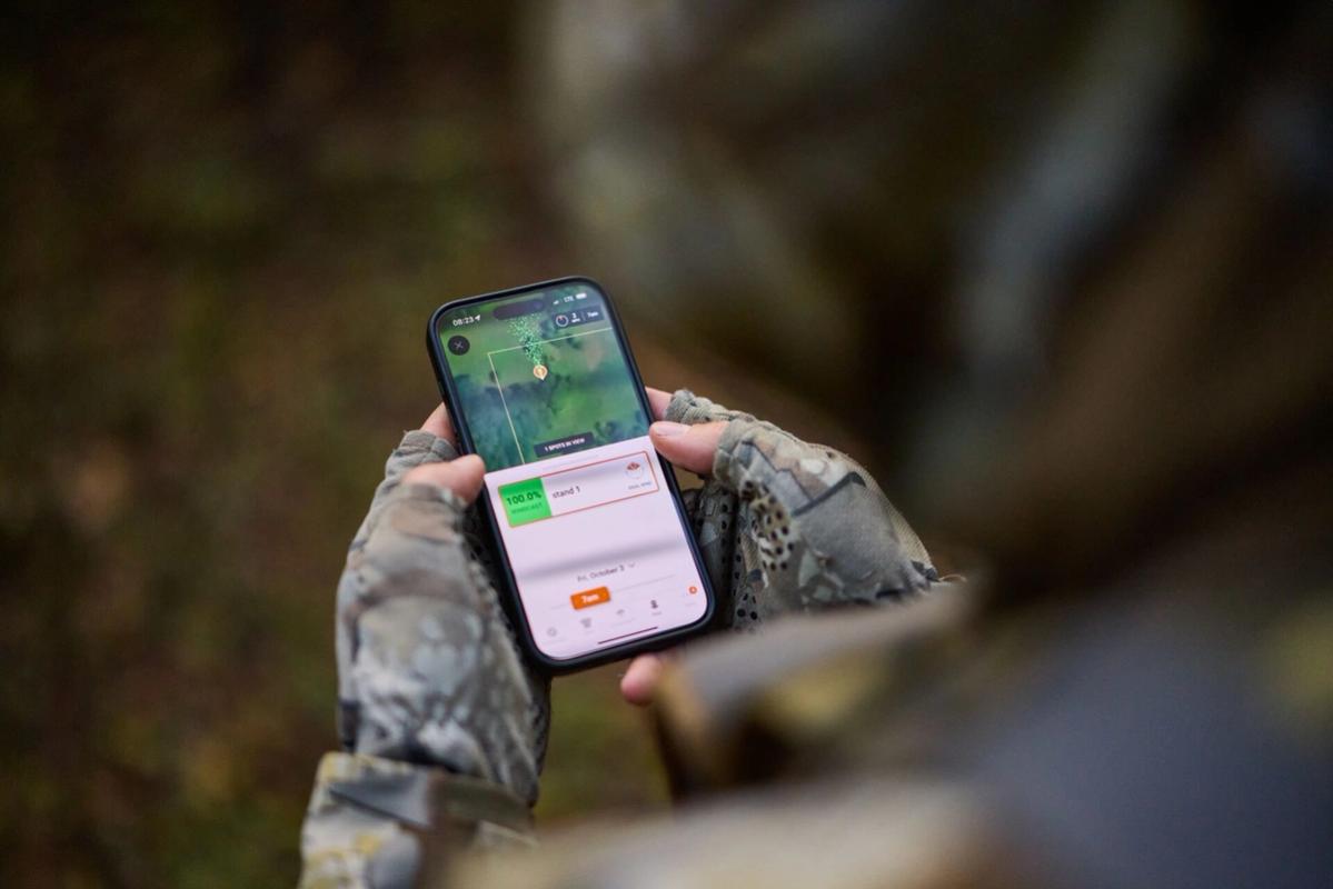 FGBLOG hunter looks at phone showing HuntWise WindCast
