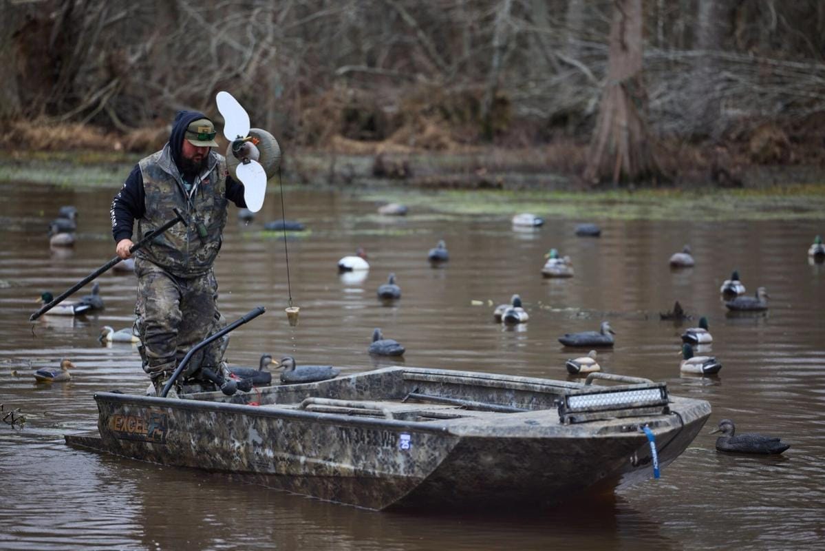 Hunter in boat sets out decoys, duck decoy hunting concept.