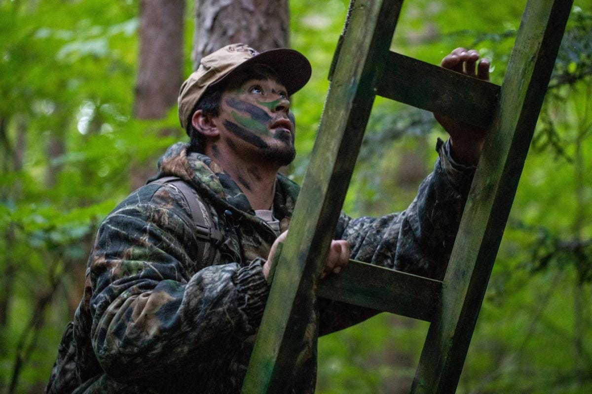 A hunter climbs a ladder to a treestand.