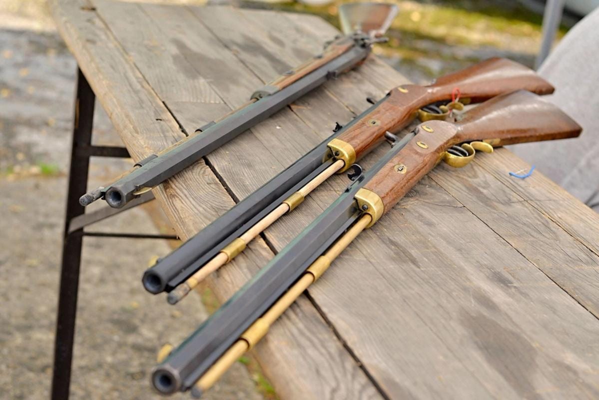 Three muzzleloader rifles on a table.
