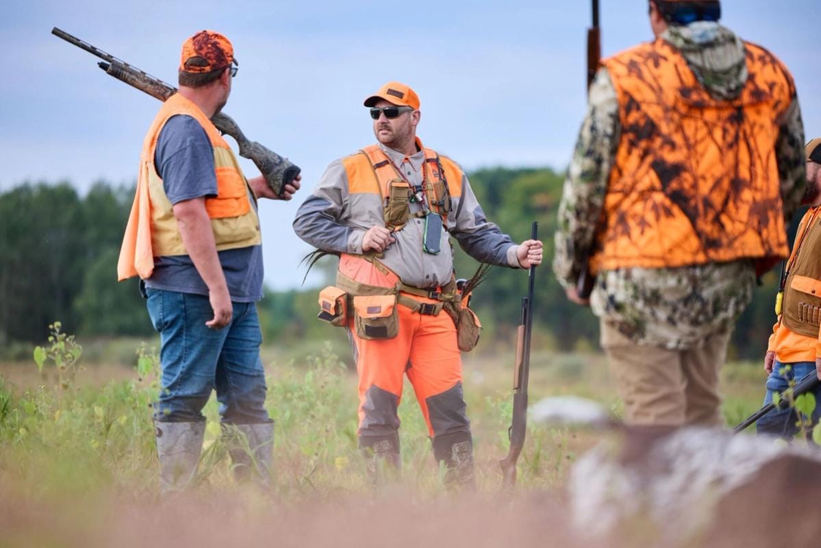 Three hunters in blaze orange ready for hunt, pheasant hunting Wisconsin concept.