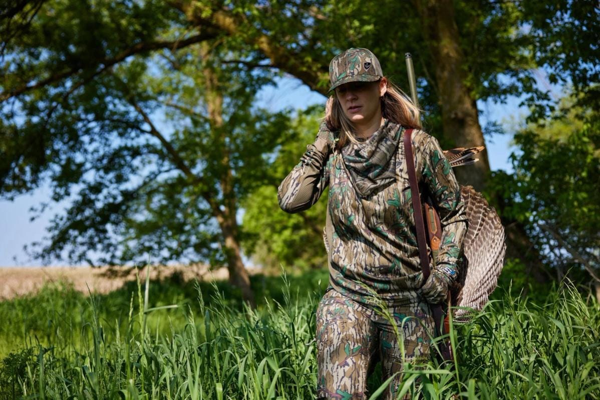 A female hunter carries a turkey after a hunt, hunting Wisconsin Turkey Zones concept.