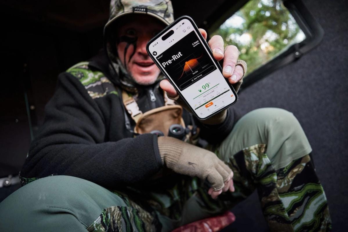 John Dudley holds up a phone showing the HuntWise hunting app RutCast feature.