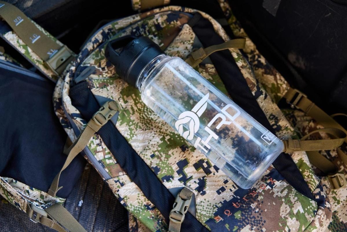 A water bottle on a backpack, hunting in summer tips for staying hydrated concept.
