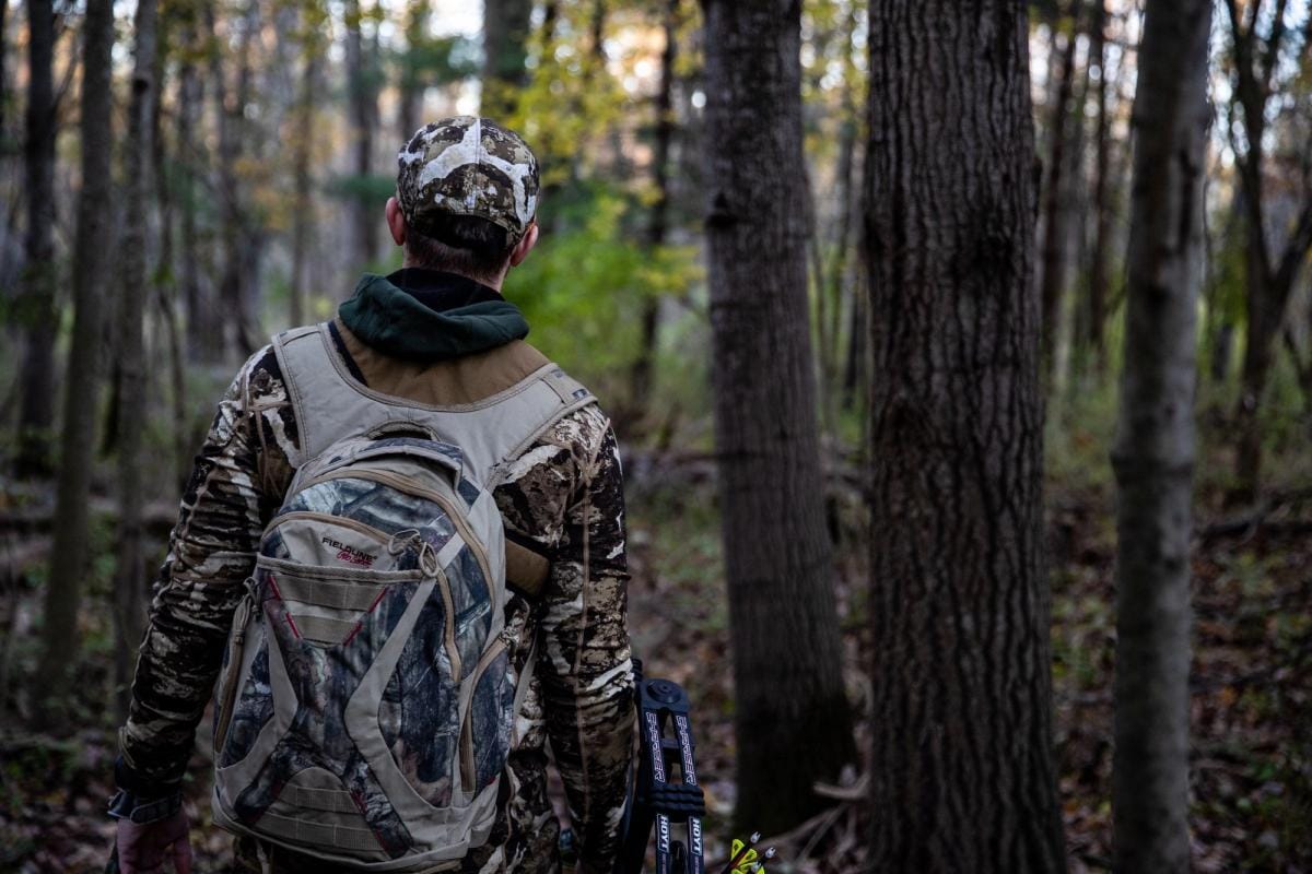 A hunter in the woods with essential hunting gear.