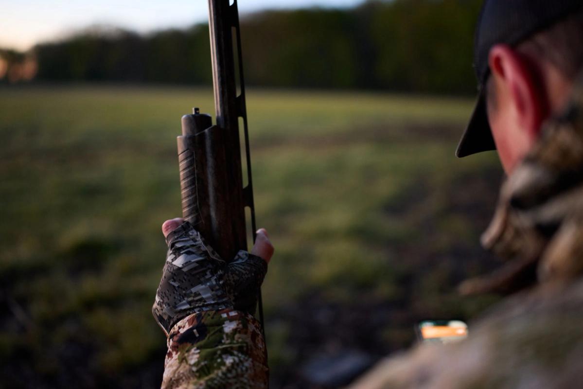 Hunter with shotgun and HuntWise app, best dove hunting shotgun concept.