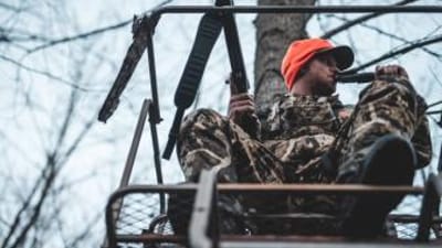 A hunter uses a deer call, calling bucks concept.