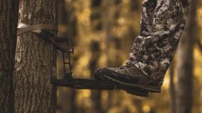 Close-up of a hunter's feet on a saddle hunting platform in a tree.