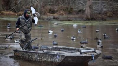 Hunter in boat sets out decoys, duck decoy hunting concept.