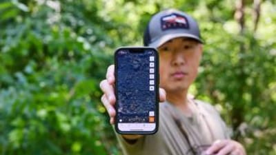 A hunter holds up a cellphone with the HuntWise hunting app on screen, prepare for hunting season concept. 