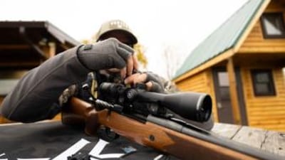 A hunter adjust a site on a hunting rifle.