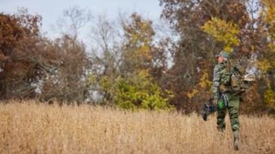 Hunter John Dudley walks a field with hunting gear, how to get permission to hunt private land concept.