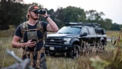 A hunter uses binoculars when scouting for deer.
