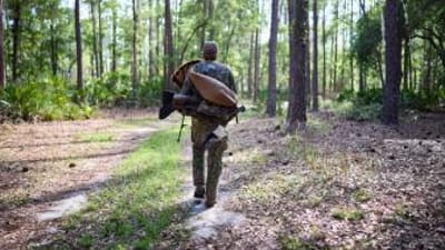 A hunter carries turkey hunting gear in the woods, how to hunt turkey in the spring concept.
