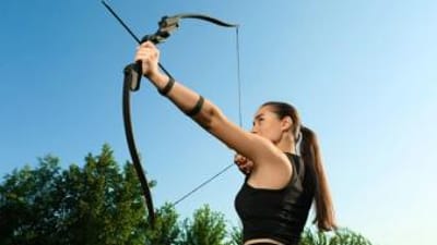 A woman draws a recurve bow.