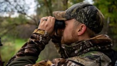 A hunter using binoculars, how to scout for deer land.
