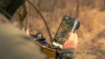 Hunter with phone in hand showing HuntWise on screen, e scouting for elk concept.
