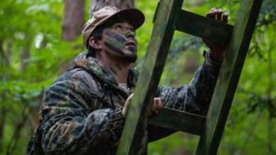 A hunter climbs a ladder to a treestand.
