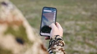 Hunter looking at phone to use topographic map app HuntWise.