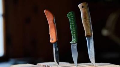Three hunting knives stuck into a wood stump, choosing hunting knives concept.