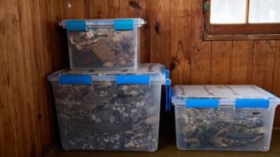 Hunting gear storage containers stacked against a wall.