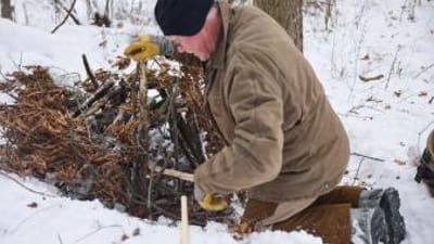 Man sets trap in the snow, PA trapping season concept.