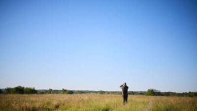 Hunter in a field in the distance, how to find walk-in hunting in Texas concept. 