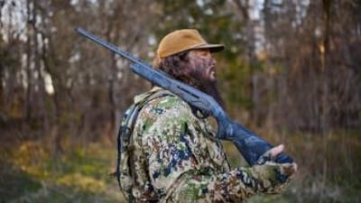 Side view of hunter with shotgun on shoulder, shotgun for hunting concept.