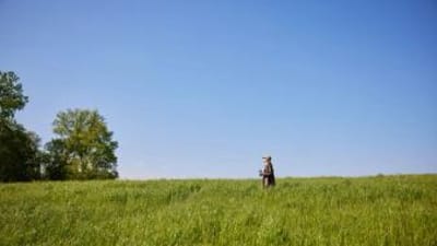 A woman in a green field, looking for private hunting land near me concept.