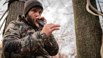 Hunter using deer call in the woods, types of deer calls concept.