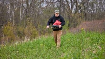 Jeff Sturgis with a seed spreader walks through a food plot, what do deer eat concept.
