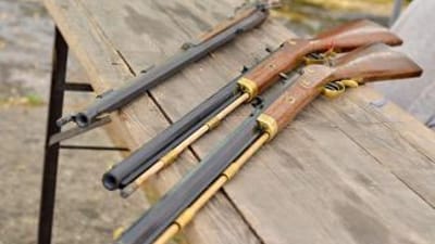 Three muzzleloader rifles on a table.
