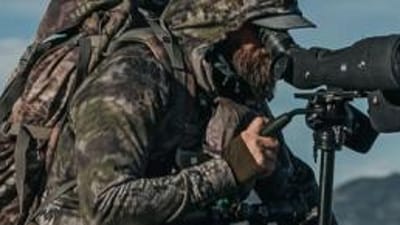 A hunter in camp use a spotting scope, best spotting scopes concept.