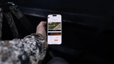 Hunter's hand holding a phone showing HuntCast in the HuntWise app.
