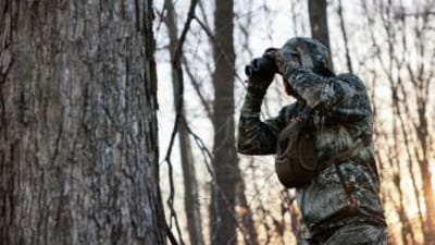 A hunter uses binoculars, best hunting binoculars concept.