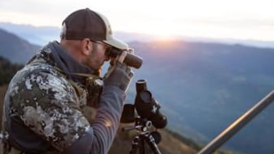 Hunter glassing on hill, high country mule deer hunting concept.