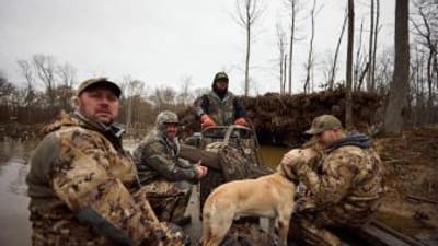 Hunters in boat with dog for waterfowl hunt, public waterfowl hunting land in Kansas concept.